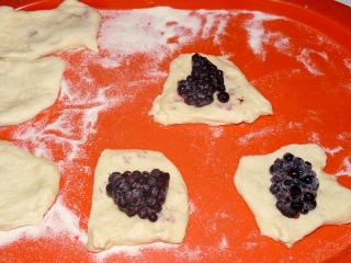 Jak udělat kynuté borůvkové knedlíky | recept Těsto necháme asi půl hodiny kynout (nebo déle, jestliže kyne pomalu). Pak je překlopíme na pomoučenou pracovní plochu a rozválíme na silnější placku, kterou rozřežeme na pravidelné čtverce. Nebo z těsta v míse ostrou lžicí nebo nožem vykrájíme stejné kousky a roztáhneme je do čtverců. Na každý položíme hromádku borůvek.